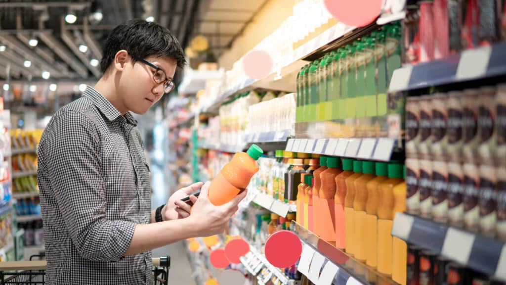 man looking at a label on the bottle of juice in a grocery store.